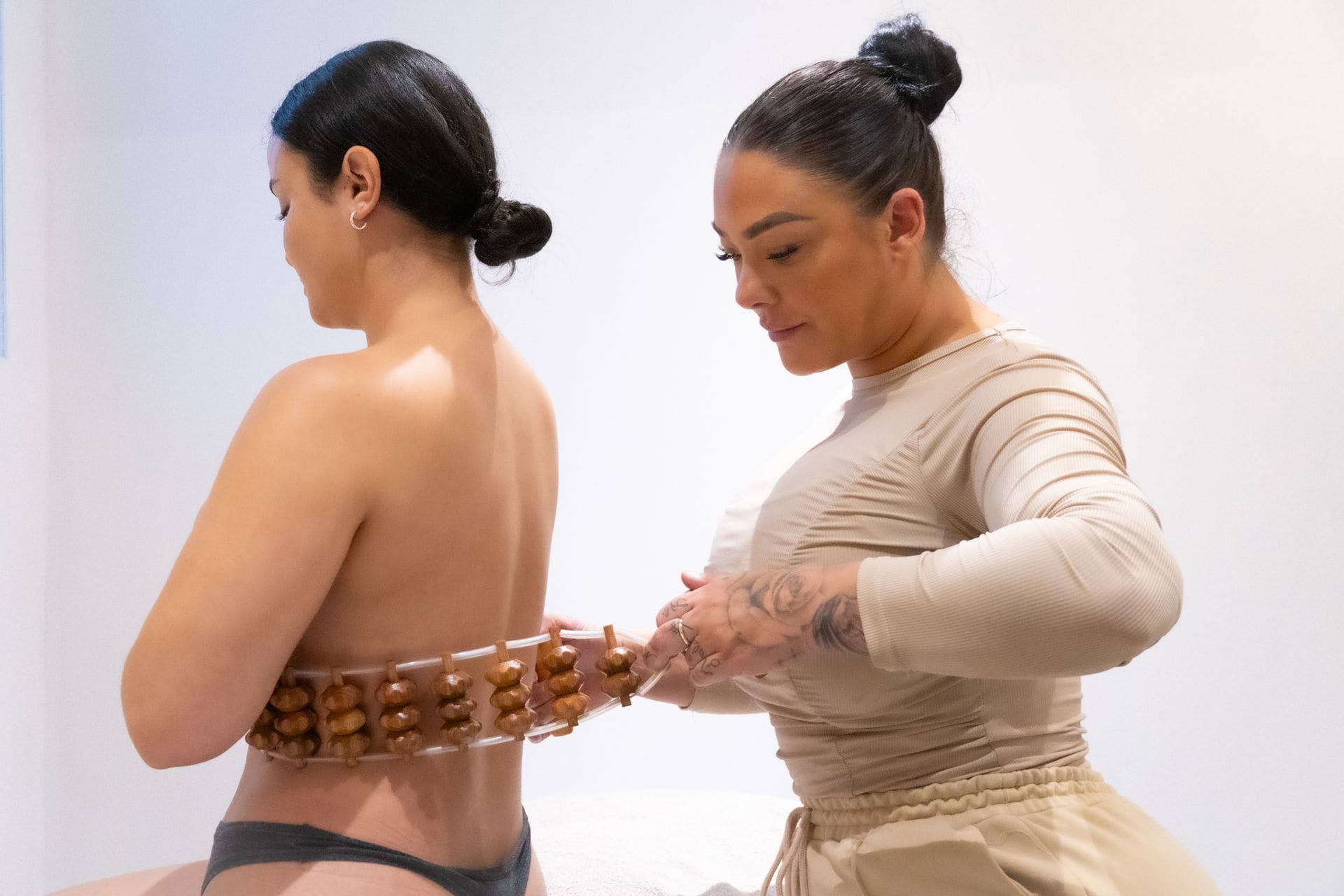 Een behandelaar past een houten massage-instrument toe op de rug van een klant.